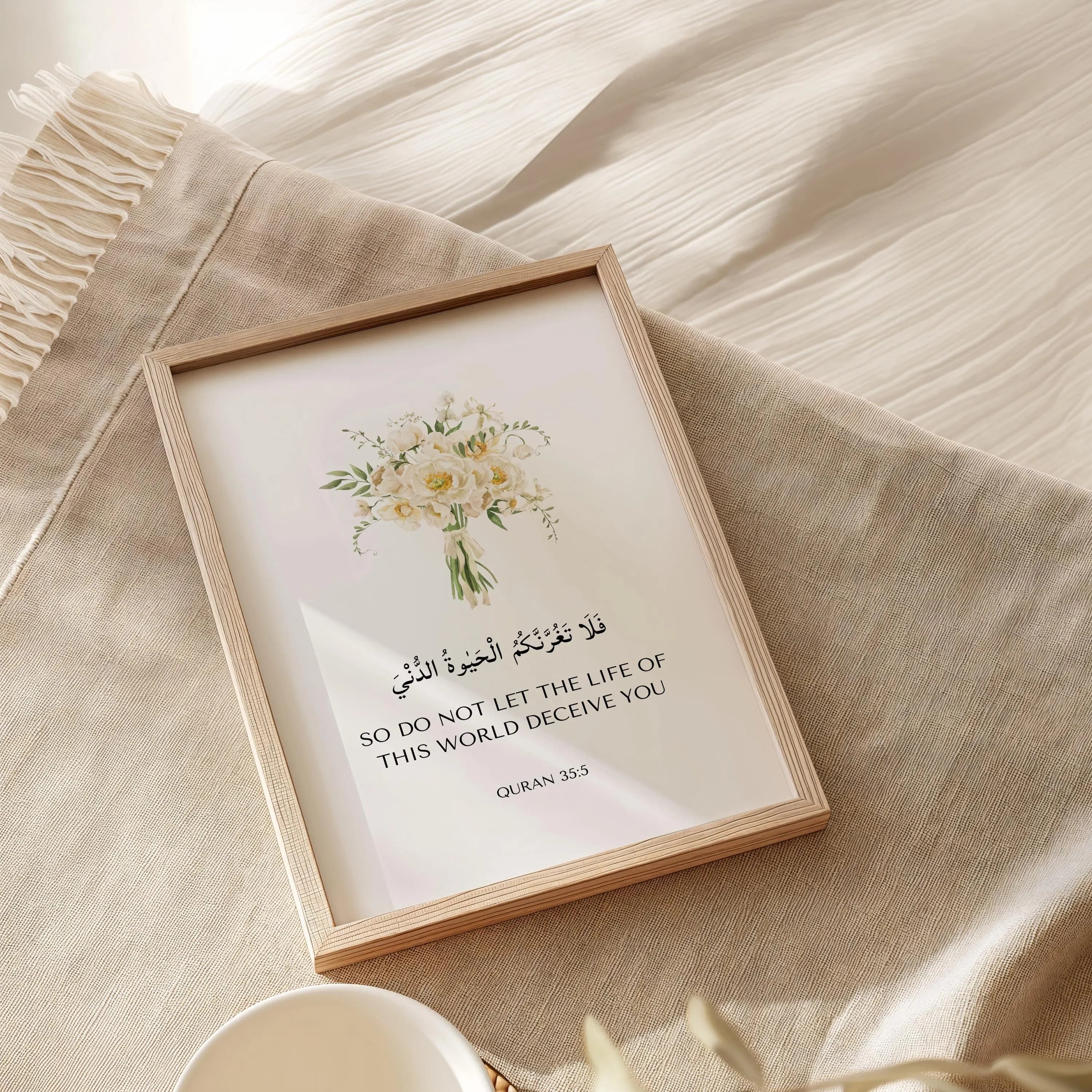 Framed islamic wall art piece featuring Quran Quote 35:5 with white flower bouquet. Set on a wooden floor. An ideal islamic art quran verse prints for islamic home decor, islamic wall decor, nursery art, or as ramadan eid gifts for muslims