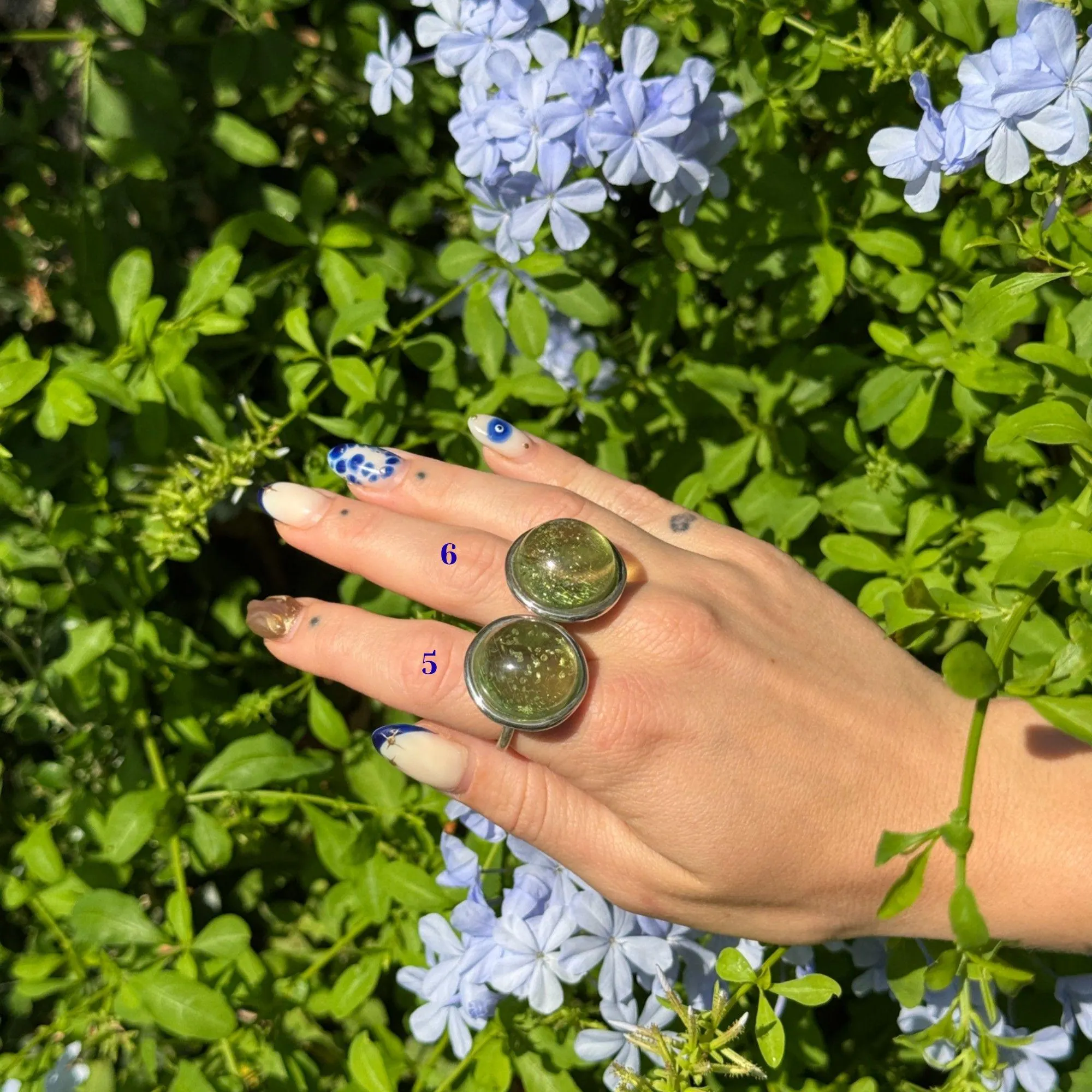 Adjustable sterling silver ring featuring two round domed green amber stones with natural shimmer