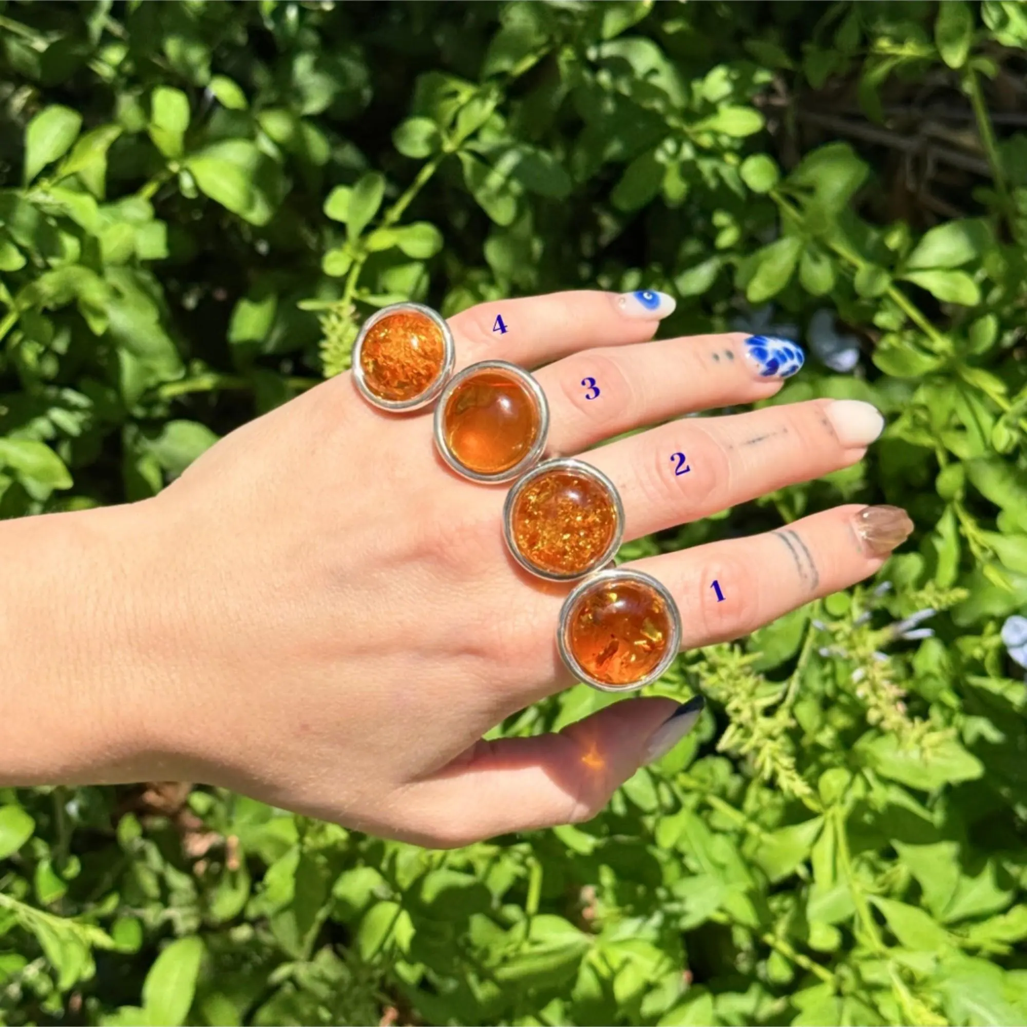 Set of four handcrafted sterling silver rings with round honey amber stones in varying textures and clarity