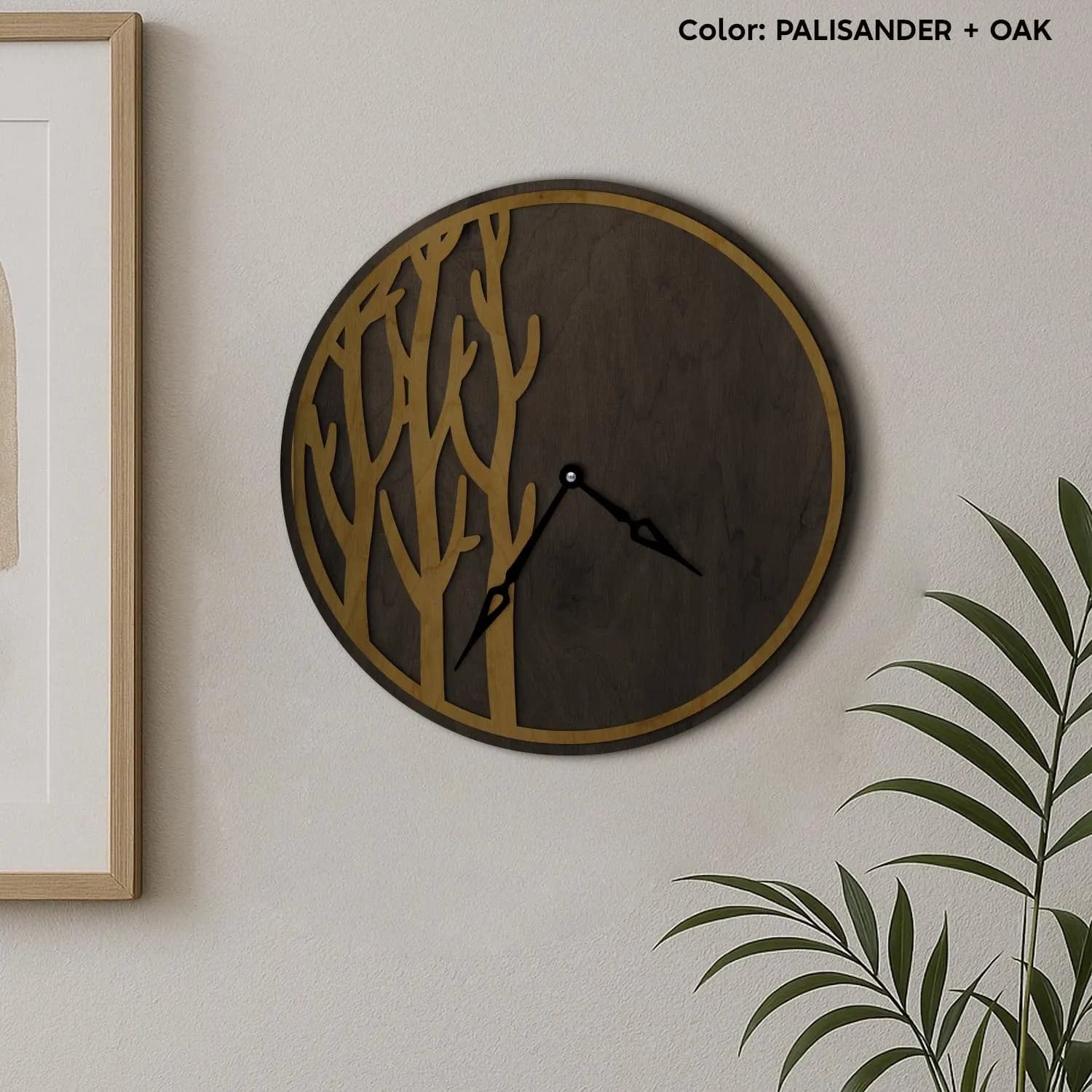 May include: A round wall clock with a dark brown face and a gold-colored tree design. The clock hands are black. The clock is mounted on a light-colored wall. The color is Palissander and Oak.