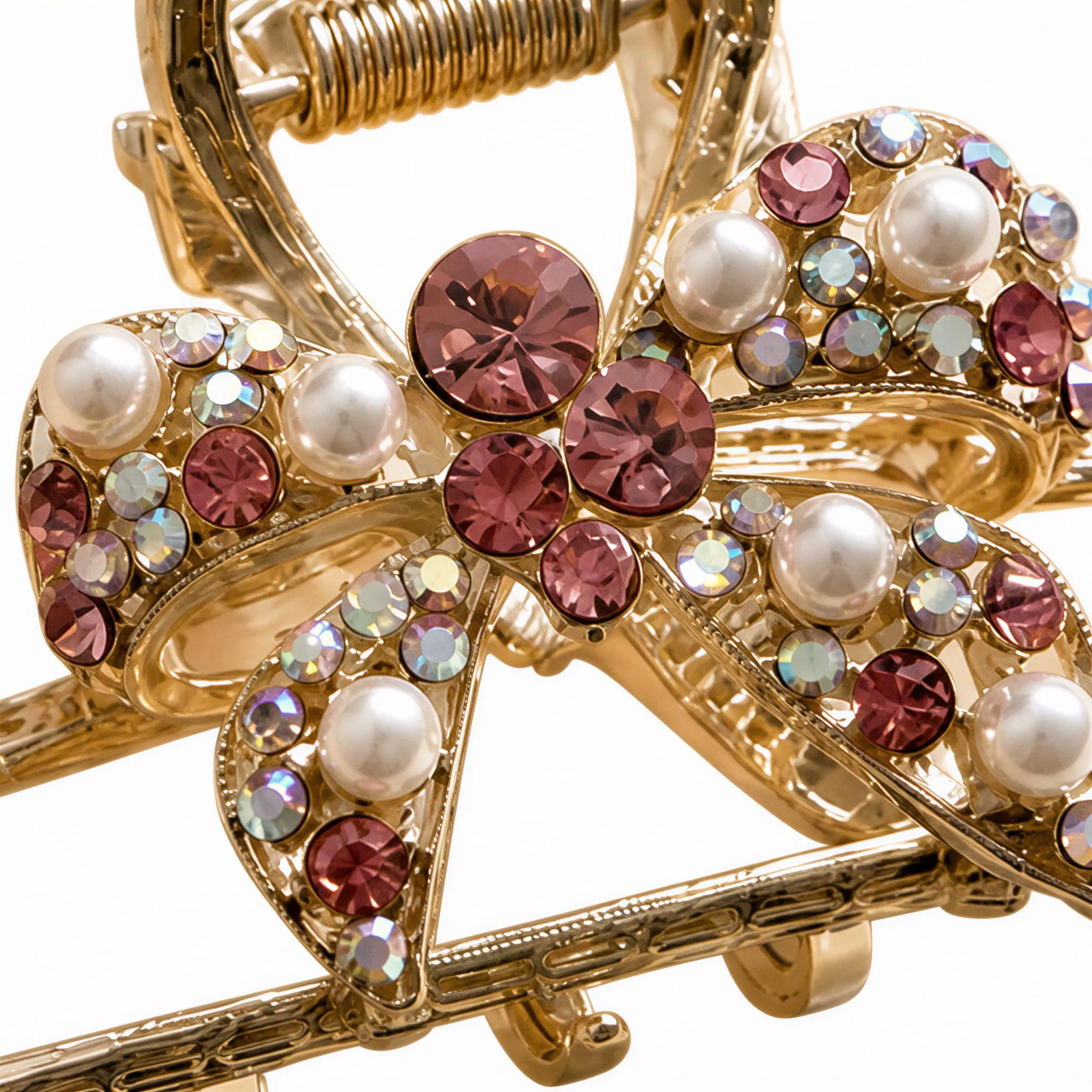 A close-up view of a decorative gold hair clip adorned with a variety of colorful gemstones, including pearls, diamonds, and rubies.
