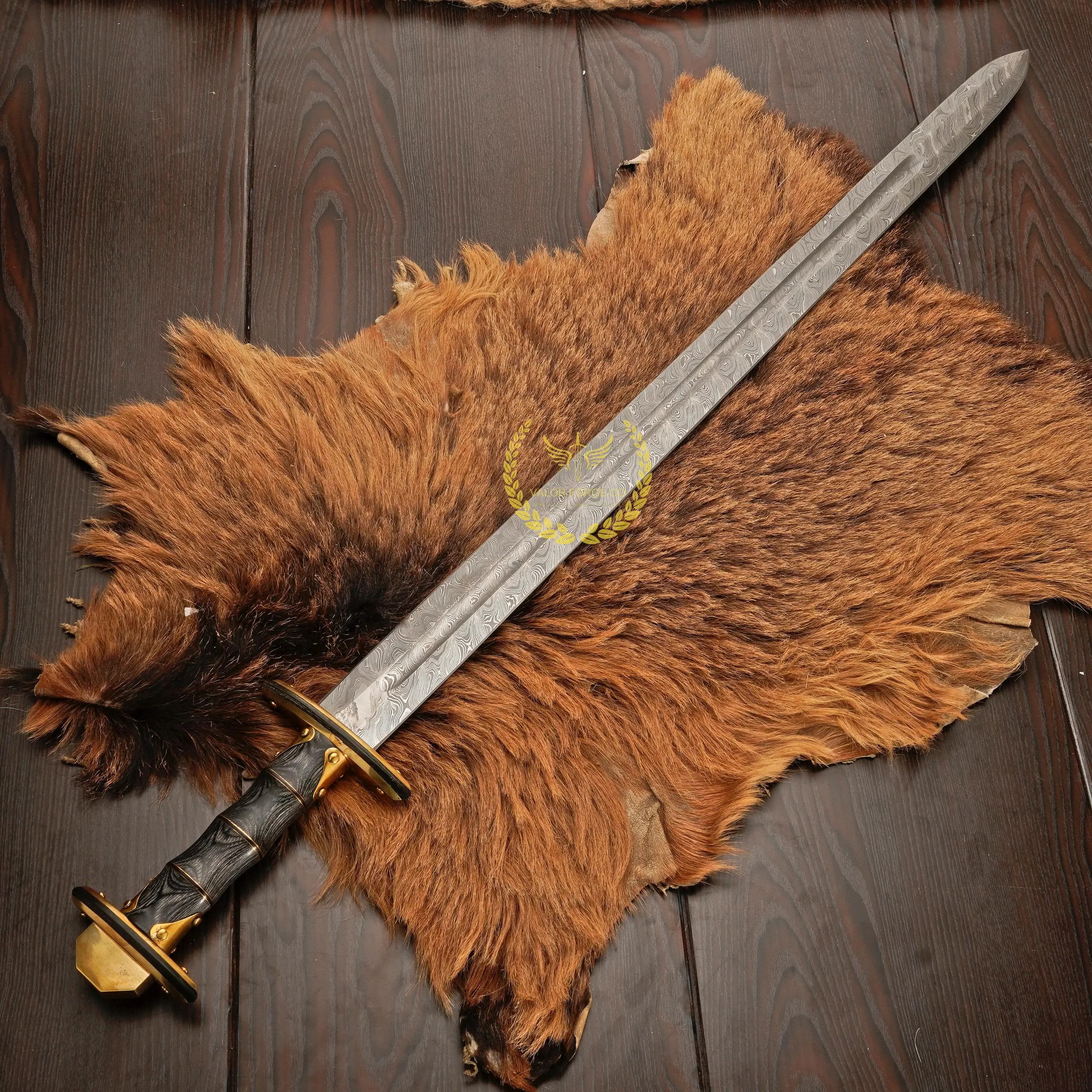 Overhead view of the damascus patterned sword blade extending across a large brown fur pelt, with the black hilt and small gold-colored guard at the lower left.