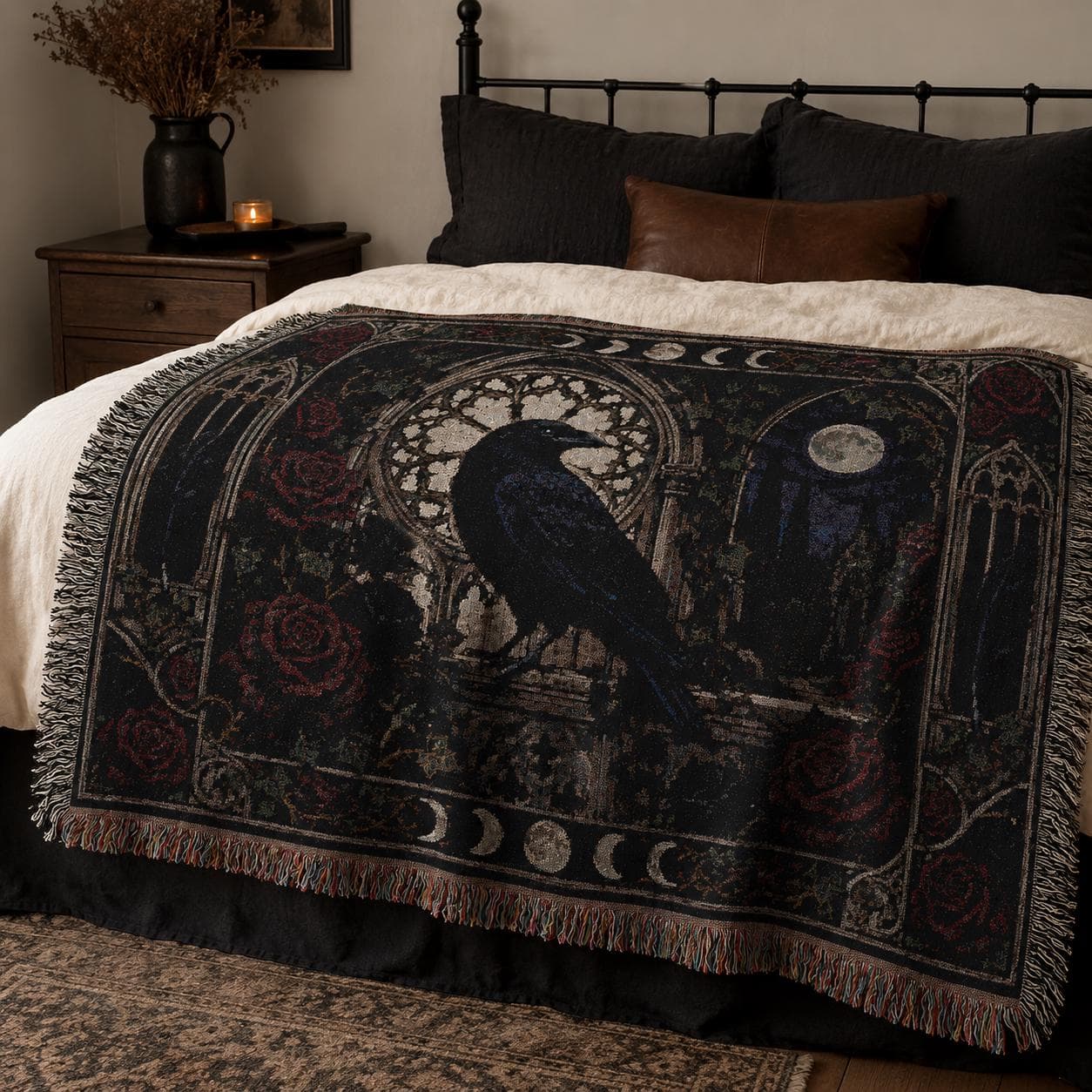 Horizontal woven blanket wall hanging with a black raven in a gothic stone archway, surrounded by red roses, moon phases, full moon, cathedral windows, dark vines, ornate border, and fringed textile edges.