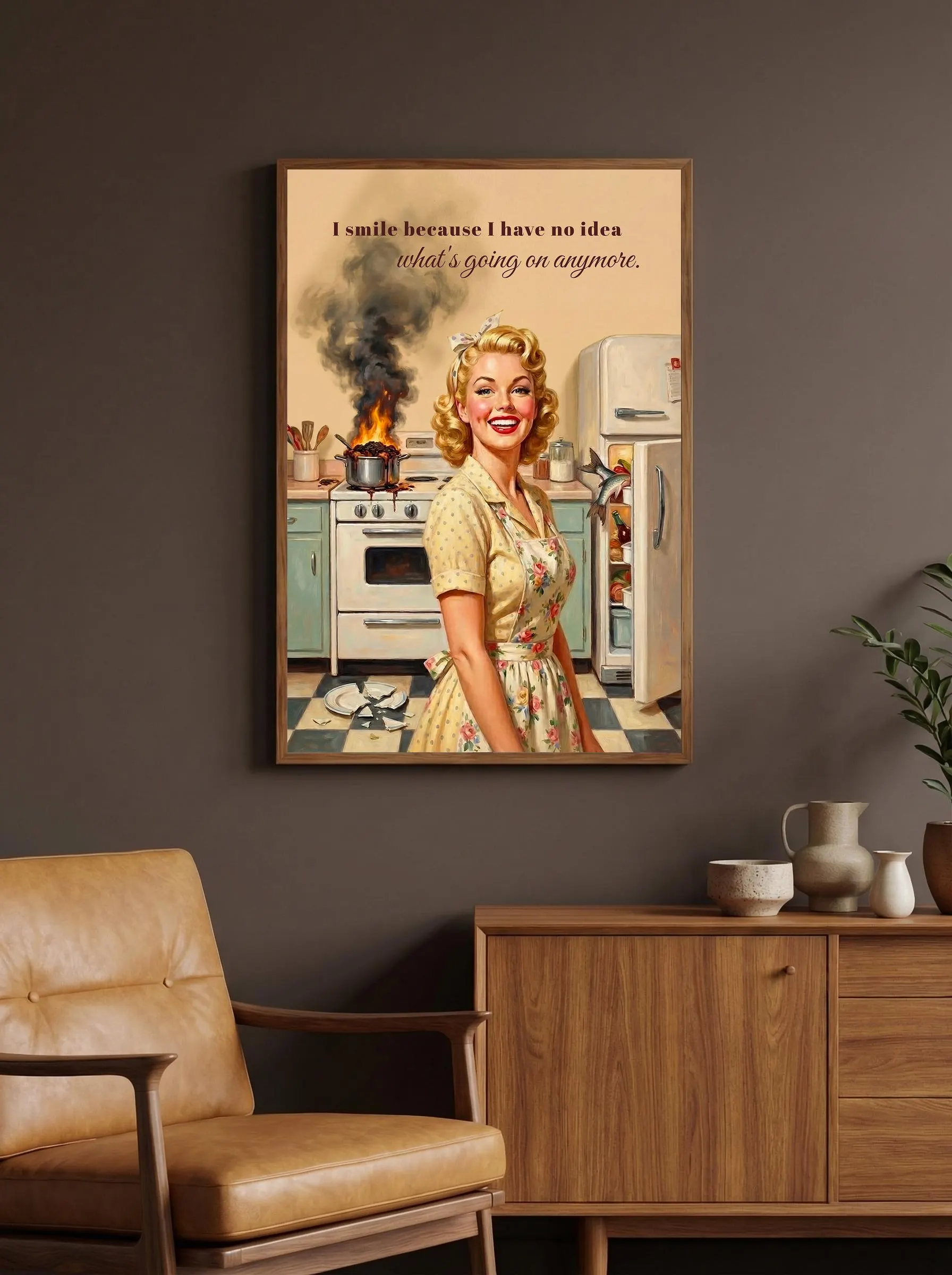 Retro housewife wall art — pin up woman in yellow floral dress, vintage kitchen setting with burning pan on stove, smoke billowing. "I smile because I have no idea what's going on anymore." brown script quote. Beige background, 1950s aesthetic.